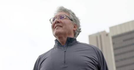 After gripping kettlebell, senior man standing at plaza and performing quadriceps stretch - Powered by Adobe