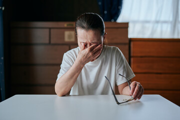 メガネを持ちながら目を押さえるシニア女性