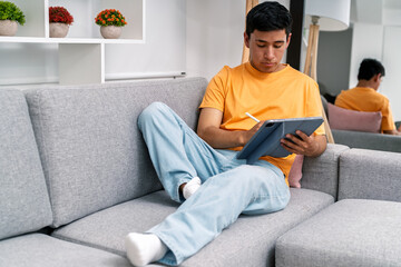 Young man working from home using tablet and stylus