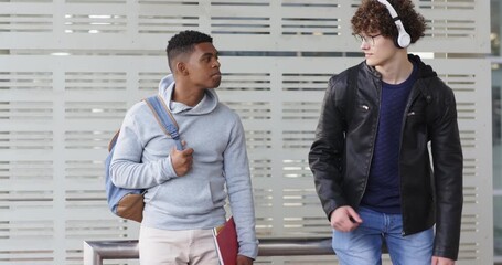 Diverse male commuters shifting gaze and listening to music on platform following newcomer entry