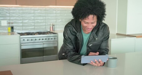 African American man leaning on kitchen island, tapping tablet, smiling and swiping for fun - Powered by Adobe
