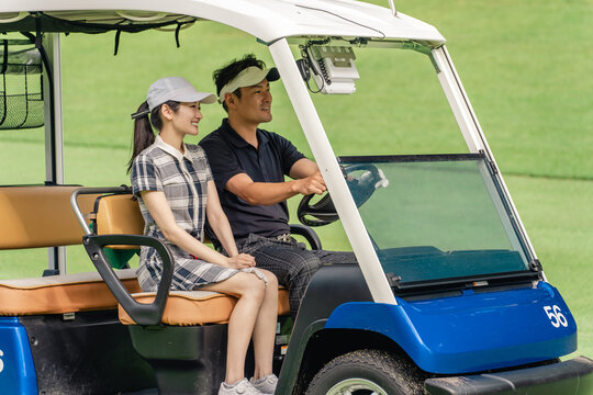 Male and female golfers riding golf carts at a golf course
- Powered by Adobe