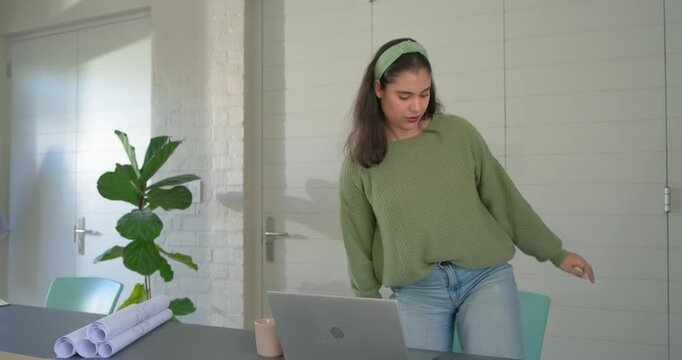Typing on laptop, Indian woman moving to colleagues in office reviewing blueprints, copy space