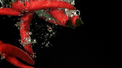 Red chili peppers fall under water. Filmed on a high-speed camera at 1000 fps. High quality FullHD footage - Powered by Adobe