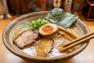 A hot bowl of ramen with egg, meat, herbs and broth