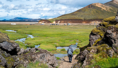 Iceland Travel - colorful scenic views of Landmannalaugar Fjallabak Nature Reserve base camp with a senior man hiking.