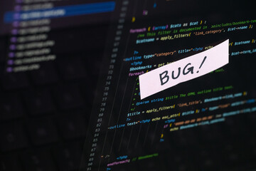 Close-up of "BUG!" Sticky Note on Coding Screen