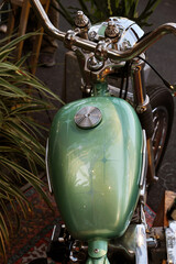 A close-up of a vintage motorcycle's fuel tank on the street.