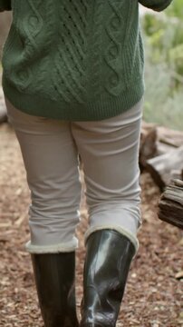 Vertical video: Stepping into trail woman wearing green sweater walking toward friend, with boots