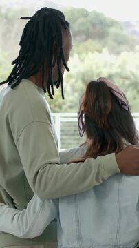 Vertical video: Putting arm round partner, taller partner on balcony glass in denim, watching trees