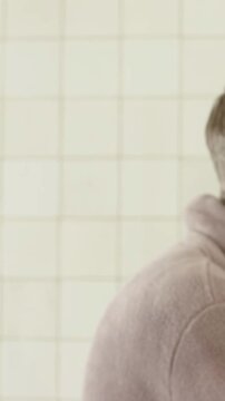 Vertical video: Panning, showing two women in towel, robe tapping pink gels at bath mirror, bonding