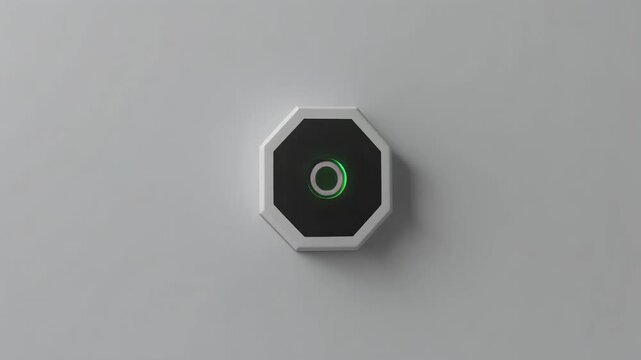 A close-up shot of an octagonal device with a glowing green circular light on a plain surface.