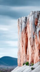 Cliff Face Standing Tall Against Cloudy Sky