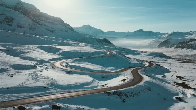 Aerial view of a winding road through a snow-covered mountain valley