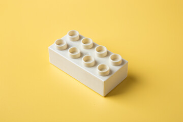 White lego block on yellow background representing childhood creativity © chee siong teh