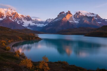 Sunset over a serene alpine lake with snow-capped mountains reflecting in calm turquoise waters