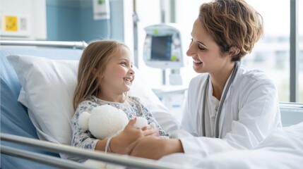 Fototapeta premium Caring female healthcare professional interacts with young girl in hospital bed, sharing a joyful moment with a stuffed toy, creating a warm and supportive atmosphere