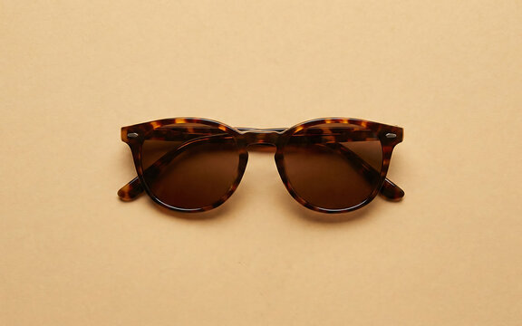 Tortoise-shell sunglasses on a sandy beige background