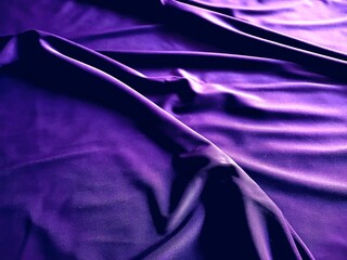 Luxury abstract background featuring dark purple or magenta satin fabric with rich texture, dramatic lighting, and deep folds. Elegant surface for design, fashion, and glamour concepts.