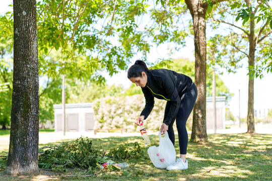 Woman plogging in park collecting plastic trash for environmental cleanup