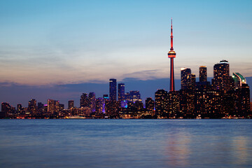 Obraz premium Toronto skyline at dusk with illuminated city lights reflecting on the water, vibrant urban night view. g.