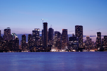 Naklejka premium Toronto skyline at dusk with illuminated city lights reflecting on the water, vibrant urban night view. g.