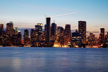 Obraz premium Toronto skyline at dusk with illuminated city lights reflecting on the water, vibrant urban night view. g.