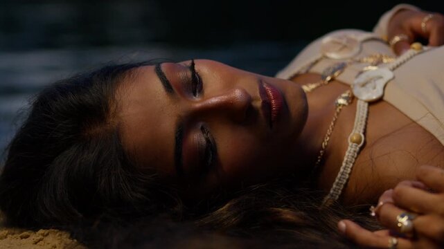 Woman lying peacefully on the sand by the water at twilight