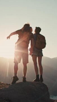 Slow motion couple mountain top sunset silhouettes holding hands pointing horizon adventure romance