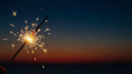 Sparkler burning brightly against a dark evening sky with a subtle gradient of colors.