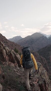 Solo traveler with heavy backpack walking uphill on rocky sunrise trail showing outdoor adventure lifestyle nature energy determination freedom exploration wanderlust mountain strength inspiring