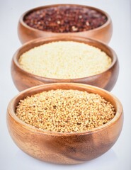 Assortment of ancient grains including quinoa, amaranth and millet in wooden bowls, isolated on white background.