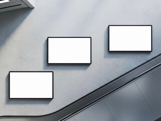 Inside a modern station interior, three rectangular blank advertising displays are mounted on a rough, textured light gray wall. Each display has a thin black frame and is placed at varying heights. A