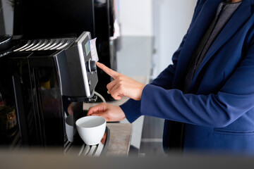 Businesswoman sitting at desk on couch in workplace or at home working on laptop and analyzing data on charts and graphs and writing on papers to make business plan and strategies for company.