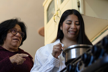 Mother teaching daughter cooking skills in a home kitchen, sharing wisdom, family tradition, and bonding over a recipe, learning new culinary techniques
