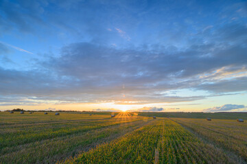 Obraz premium The breathtaking sunset over the lush green fields, accompanied by a vibrant and colorful sky