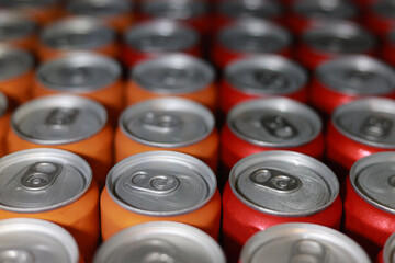 Close up background of many red and orange aluminum cans in row. soft focus abstract view of large group of soft drink containers ready for distribution