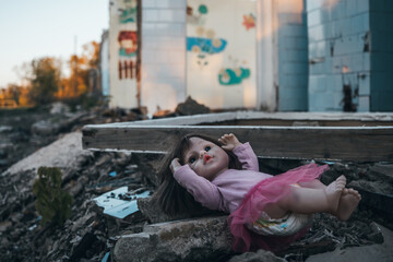 the concept of destroying childhood by war. frightened doll against the background of a tank and a burnt-out building. concept of suffering of children and civilians in war.