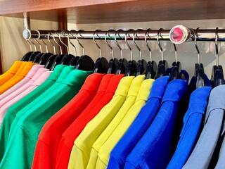 Stylish luxury men's clothing store, new colorful cotton polos hanging on hangers in the store