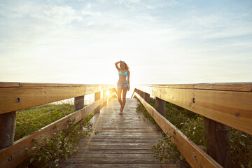 Travel, sunset and woman on bridge with swimwear, wellness and fresh air on weekend break. Happiness, flare and female person in nature with space, adventure and summer evening in Australia.