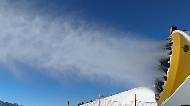 Passo del Tonale, Italy. Snowmaker in action at ski resort spraying artificial snow. Winter contest. Alps