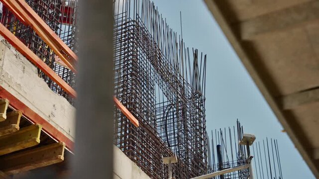 Construction site. Dense steel rebar grid rises above a city construction site, framed by formwork and beams against a pale blue sky. structural skeleton before the concrete pour urban development,