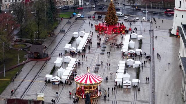 Aerial view of a Christmas market in Vilnius, showing the decorated tree, carousel, and vendor rows on the Cathedral Square during a cold festive day.