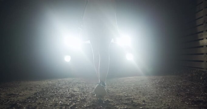 Night walk in a dimly lit area with footsteps on gravel and headlights illuminating the surroundings