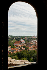 Historic buildings among green trees in a European city. A panoramic bird's-eye view of the historic city from the window of a tall old castle. June 1, 2025, Vilnius, Lithuania.