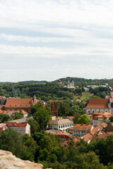 Historic buildings among green trees in a European city. A panoramic bird's-eye view of the historic city from the window of a tall old castle. June 1, 2025, Vilnius, Lithuania.