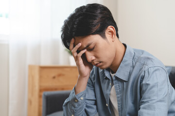 Stressed male feeling depressed and lonely on the sofa in the house.