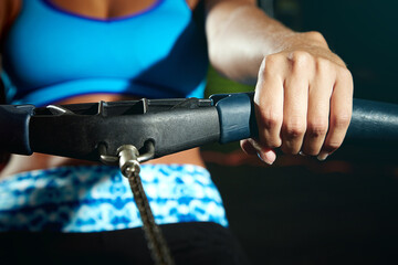 Hands, rowing machine and woman with exercise, wellness and workout with endurance, handle or routine. Closeup, athlete and person in health facility, challenge and equipment with core training