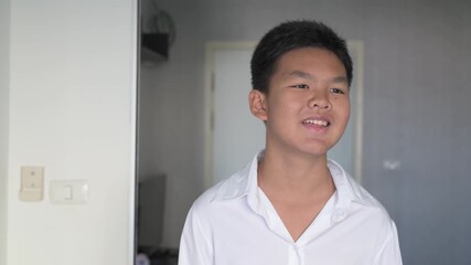 Portrait of Asian teenage boy smiling and thinking at home indoors
