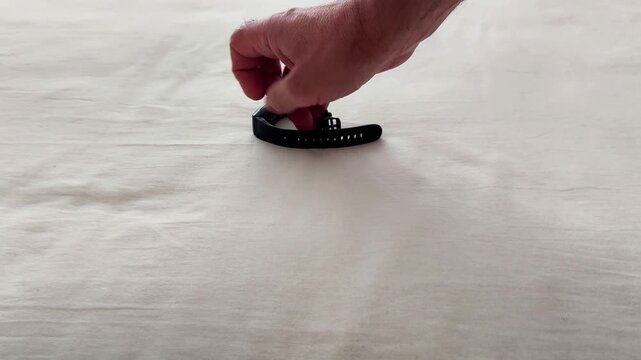 A worn wearable strap rests on a soft fabric surface, showing frayed edges and visible damage as the camera moves gently across the texture and material details